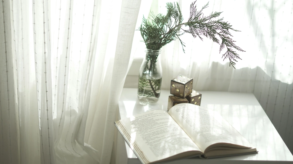 Rincón de depa rentado con libro, luz natural y cortinas largas que crean un ambiente cálido y habitable.
